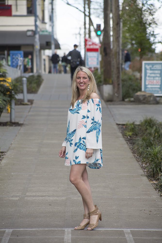 A woman in white and blue dress standing on sidewalk.