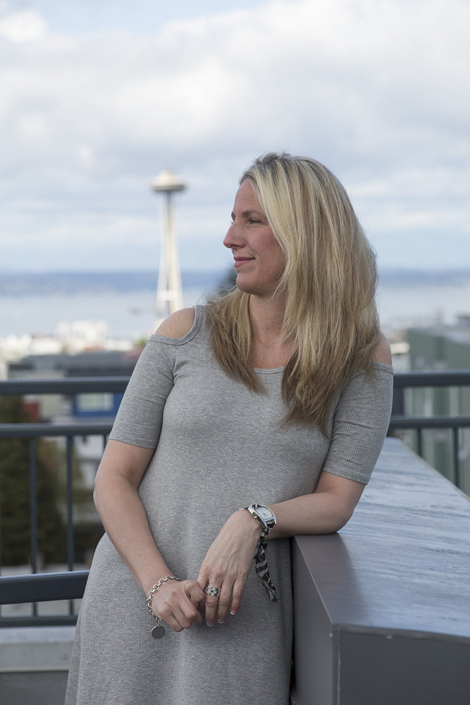 A woman standing on top of a building near the ocean.