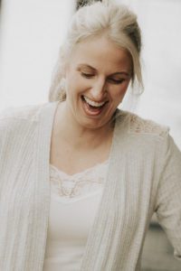 A woman laughing with her eyes closed.