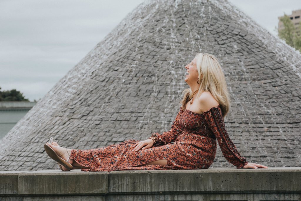 A woman sitting on the side of a building.