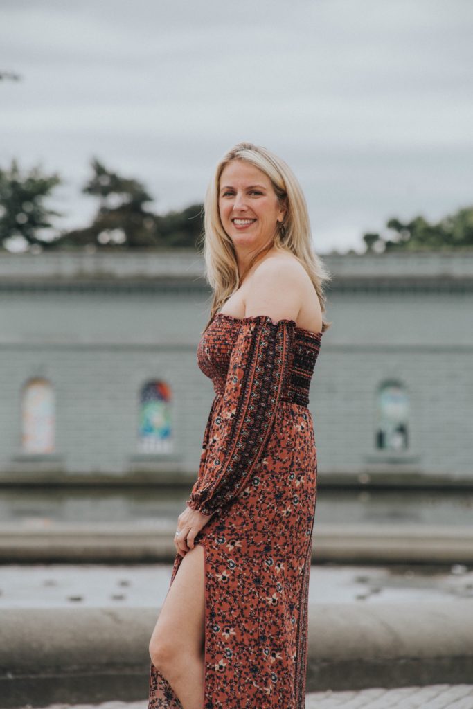 A woman in a dress standing next to water.